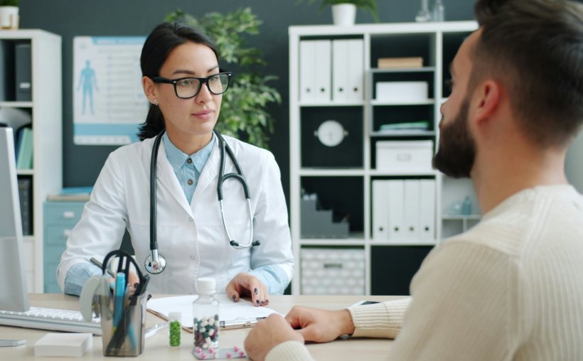 A doctor and her patient are sitting at a desk in the GP office