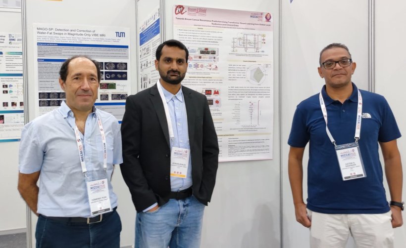 Three researchers standing in front of their poster presentation at a medical...