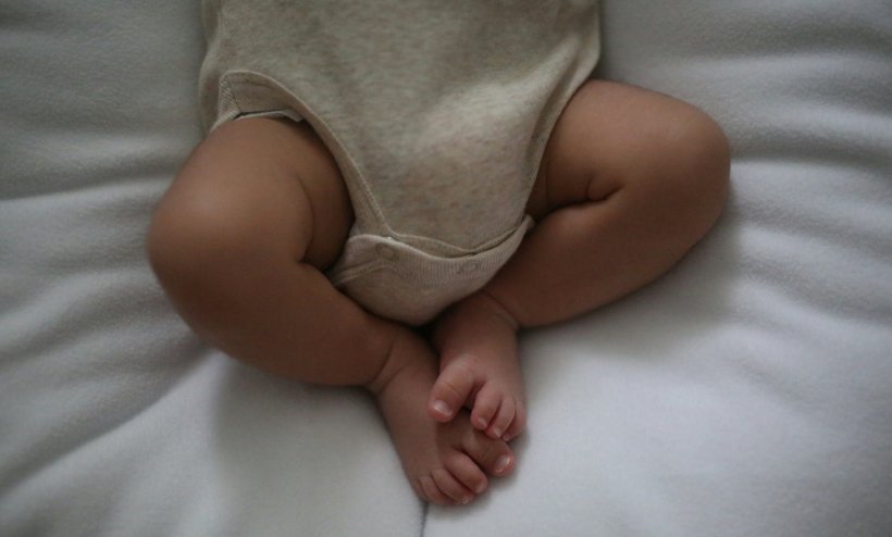A baby is lying on a soft blanket. The photo shows the infant from the hips down