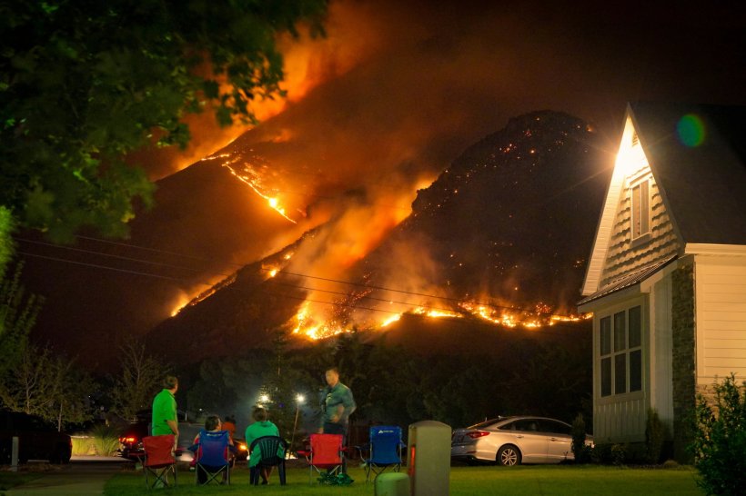 A group of people sitting in lawn chairs in front of a wildfire