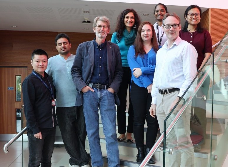 A group of eight people posing on a flight of stais for a group photo