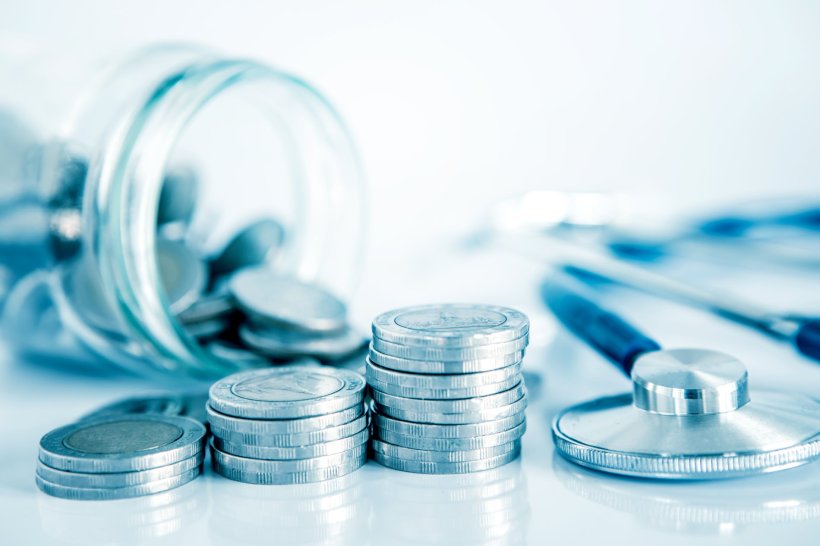 Silver coins arranged on a table next to a stehoscope