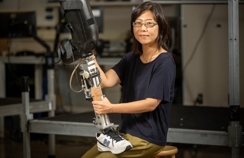 A woman is holding a robotic prosthetic leg with both hands