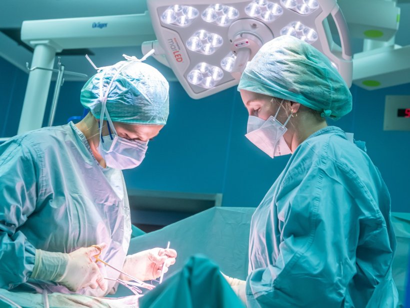 Zwei Chirurgen stehen im OP um einen Patienten außerhalb des Bildes