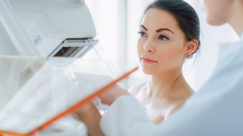A young woman is undergoing a mammography scan for breast cancer screening