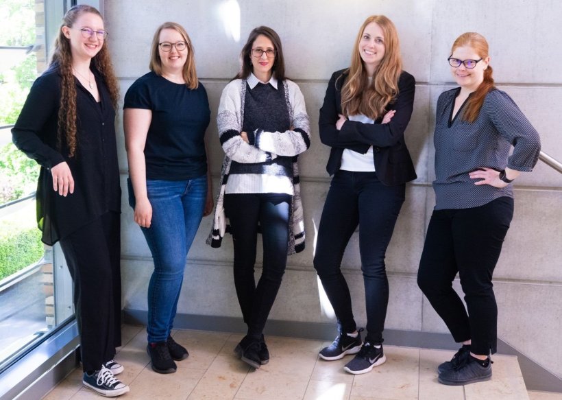 Fünf Frauen stehen in einem Treppenhaus für ein Teamfoto nebeneinander