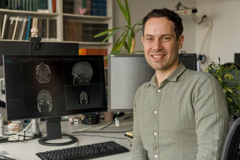 Dr. Niclas Hagen sitzt an einem Schreibtisch. Auf dem Computer-Monitor links...