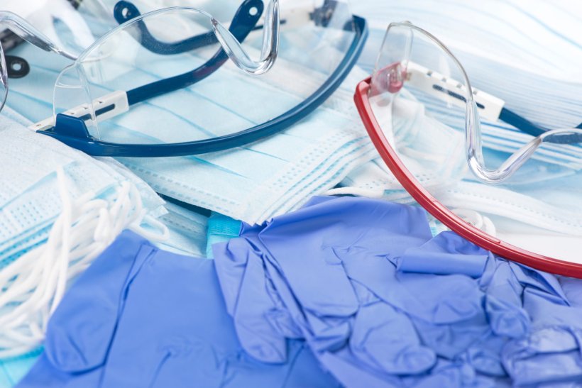Medizinische Schutzausrüstung liegt auf einem Tisch: blaue Gummihandschuhe,...