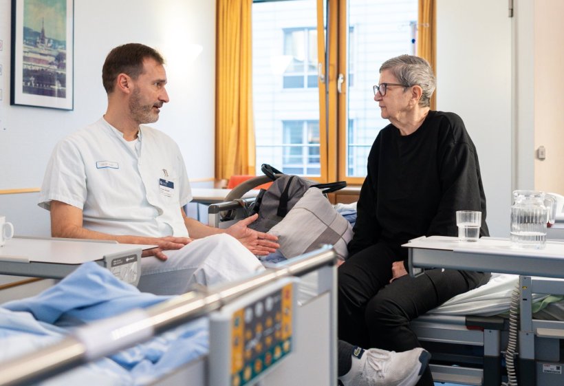 Ein Arzt sitzt seiner Patientin gegenüber in einem Klinikzimmer