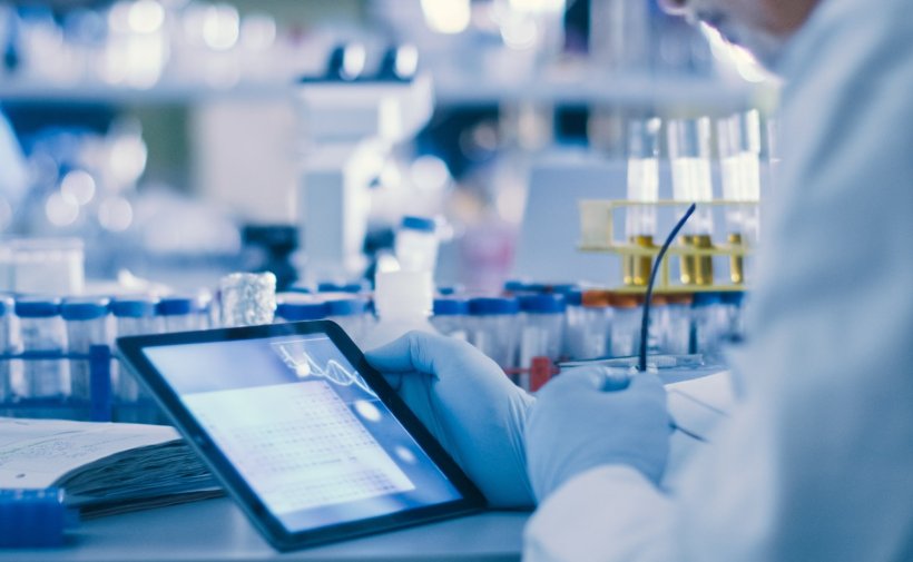 A scientist is using a tablet computer in a modern high-tech laboratory for...