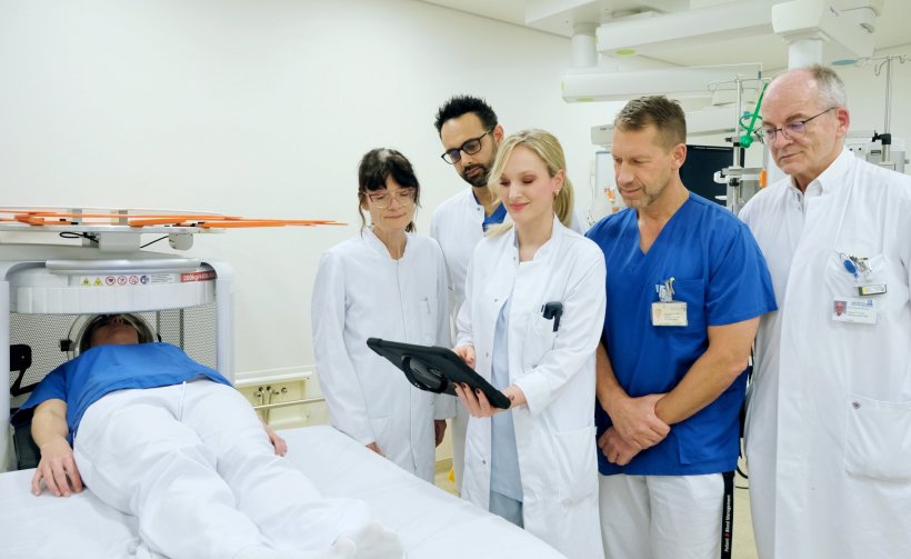 Fünf Mediziner stehen am Krankenbett eines Patienten, der mit dem Kopf in...