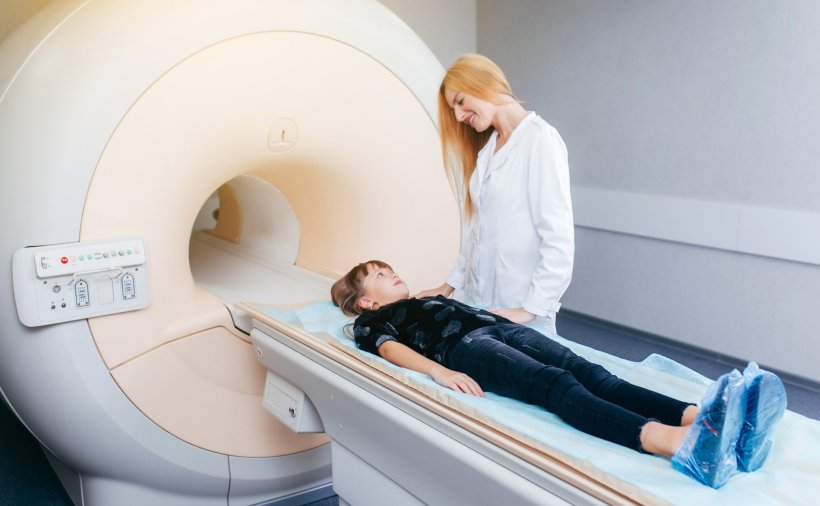 Ein Kind liegt auf der Liege eines MRT-Scanners im Behandlungsraum eines...