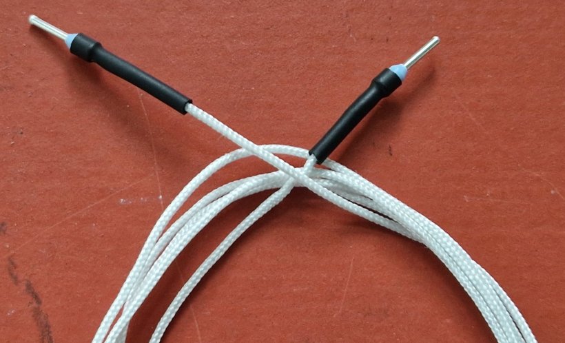 Ein aufgewickeltes Kabel mit weißer Stoff-Ummantelung liegt auf einem...