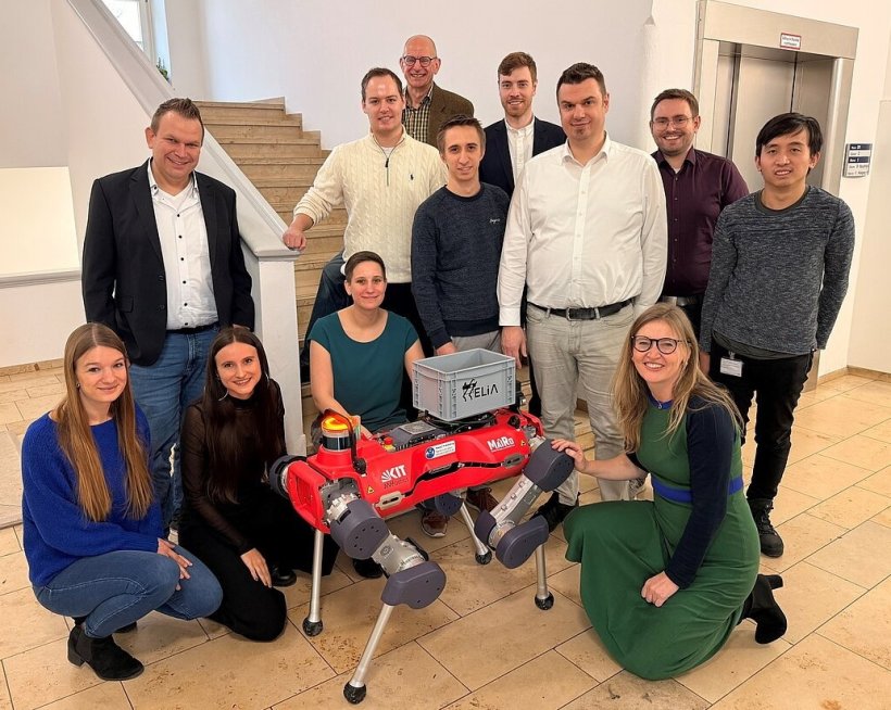 Zwölf Personen stehen im Treppenhaus eines Krankenhauses um einen...