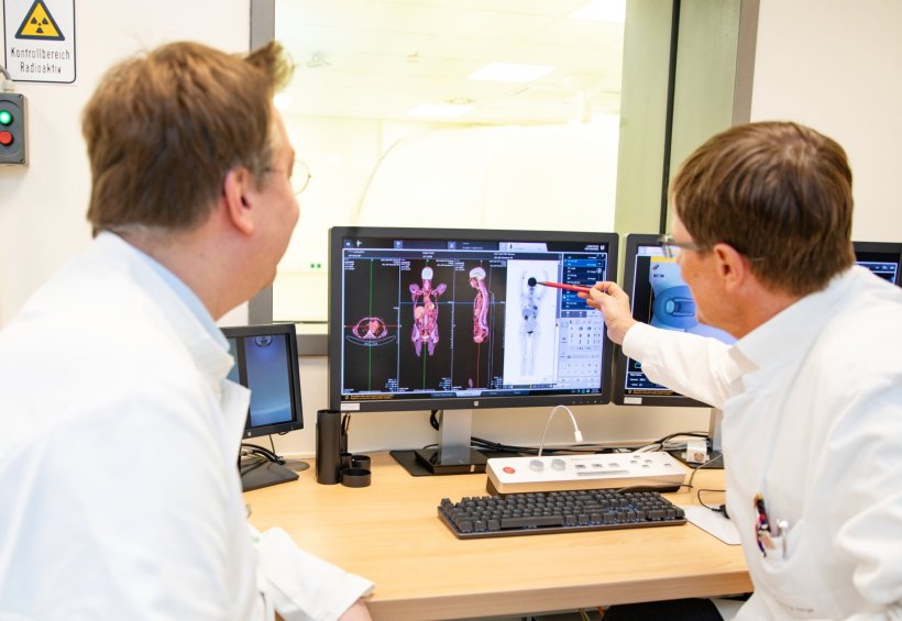 Zwei Mediziner blicken auf einen Monitor, der eine Ganzkörper-PET-CT-Aufnahme...