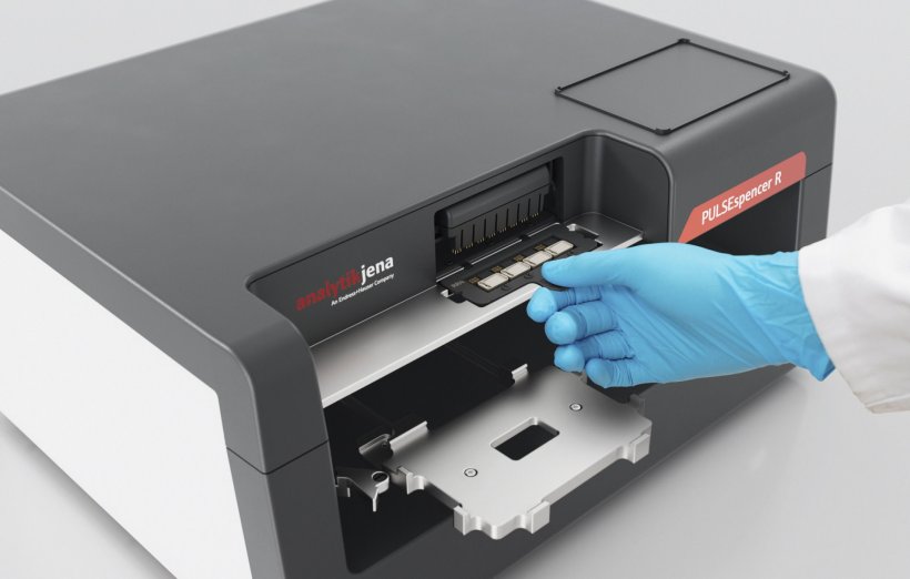 The hand of a laboratory expert wearing a blue protective glove operating a...