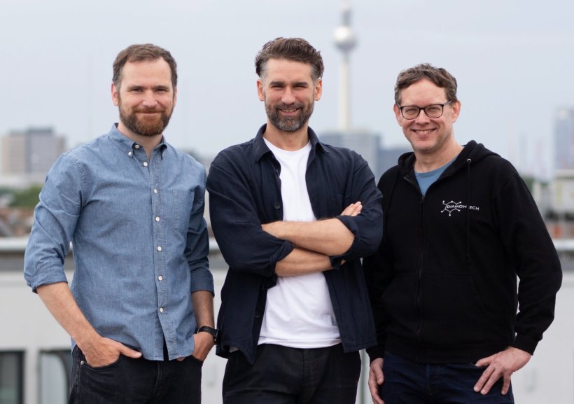 Drei Männer stehen für ein Teamfoto nebeneinander. Im Hintergrund ist der...
