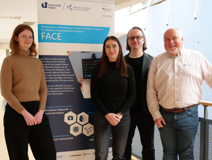 Vier Personen stehen vor einem Präsentations-Plakat für ein Teamfoto