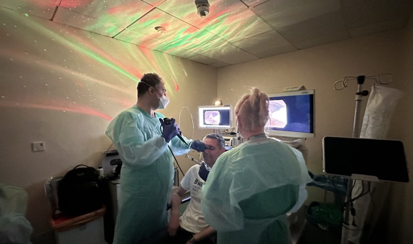 Doctor performing an endoscopy on a sitting patient. The room is lit by...
