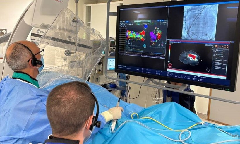 Two cardiologists are performing cardiac mapping on a patient in a hospital....