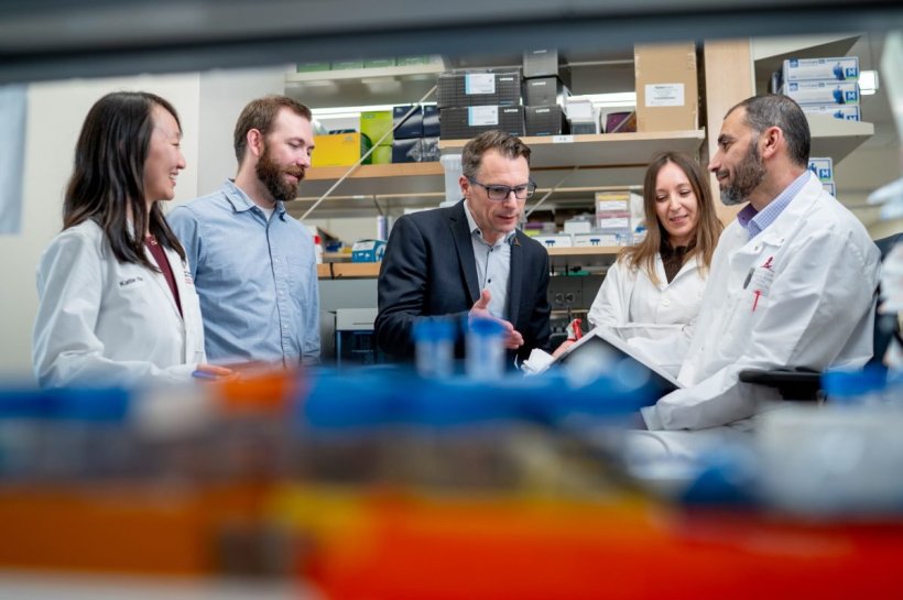 Five scientists are sitting around a table in a laboratory, discussing...