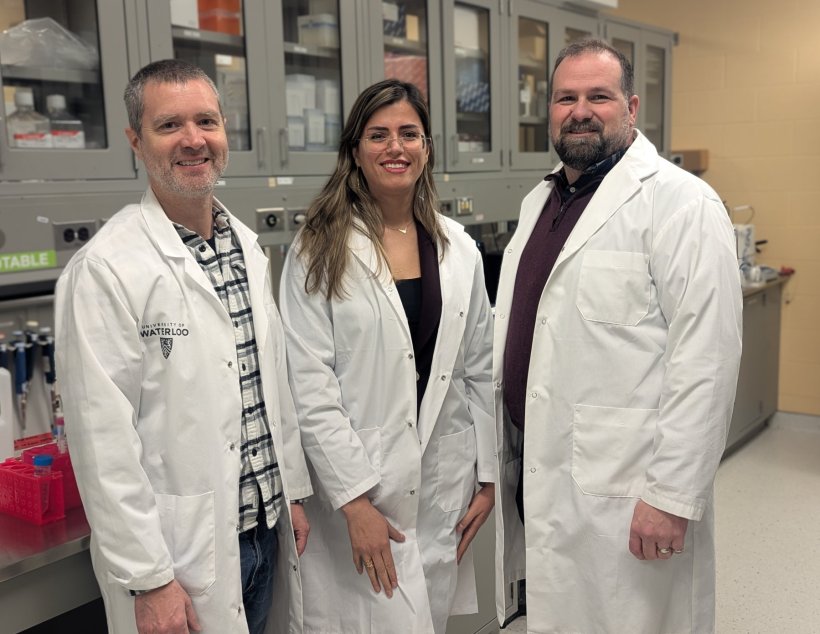 Three chemical engineers in white lab coats are standing next to each other for...