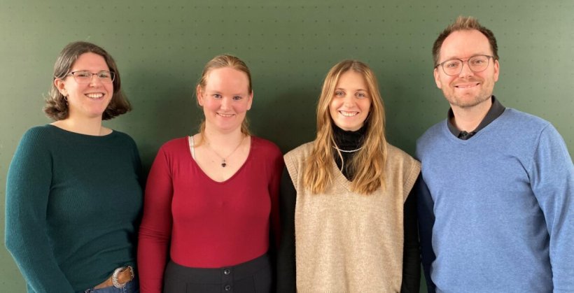 Vier Forscher stehen für ein Teamfoto vor einer dunkelgrünen Schultafel