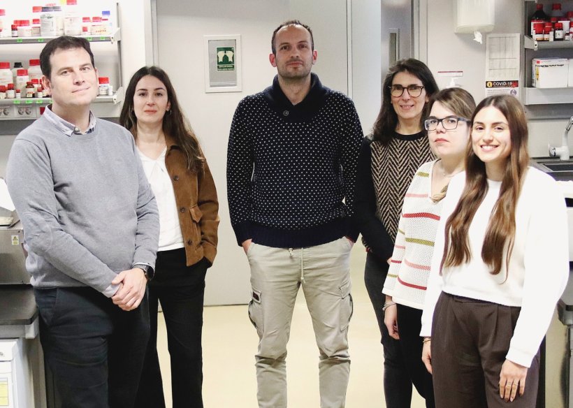 Six researchers standing in a row in a medical laboratory for a team photo
