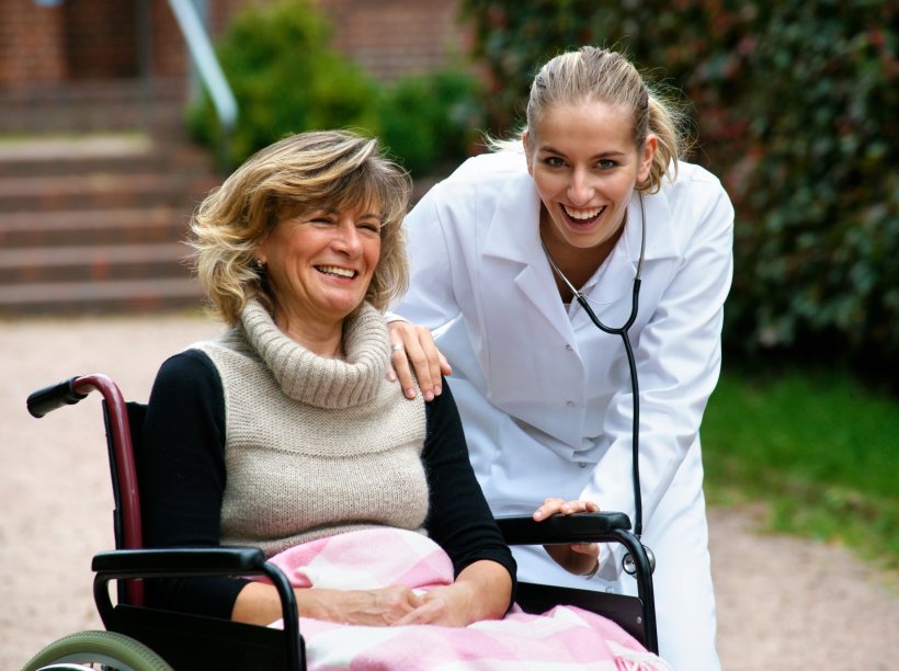 A woman in a wheelchair and a doctor are outside. The doctor has her hand on...
