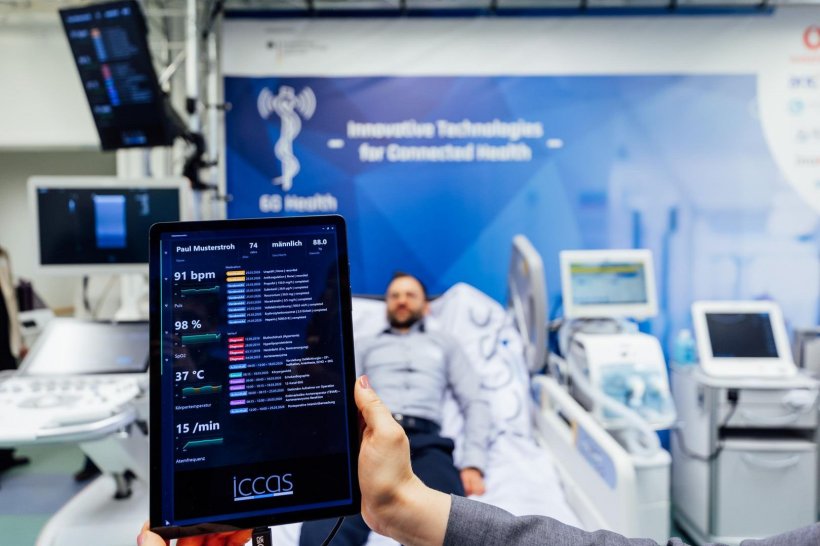 Eine Hand hält ein Tablet mit einer Liste von Patientendaten hoch. Unscharf im...