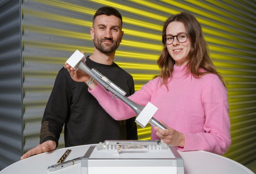 Paul Motzki und Floria Wein stehen an einem runden weißen Tisch, auf dem Teile...