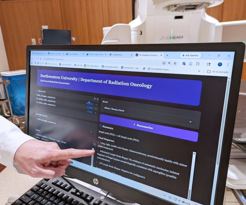 A computer screen showing a cancer pathology report. From the left, a hand is...