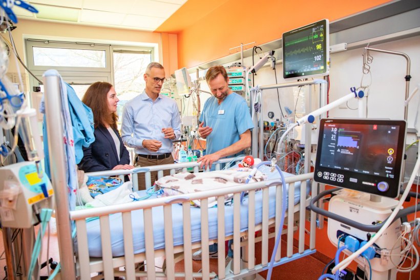 Drei Mediziner stehen in der pädiatrischen Intensivmedizin an einem Babybett...