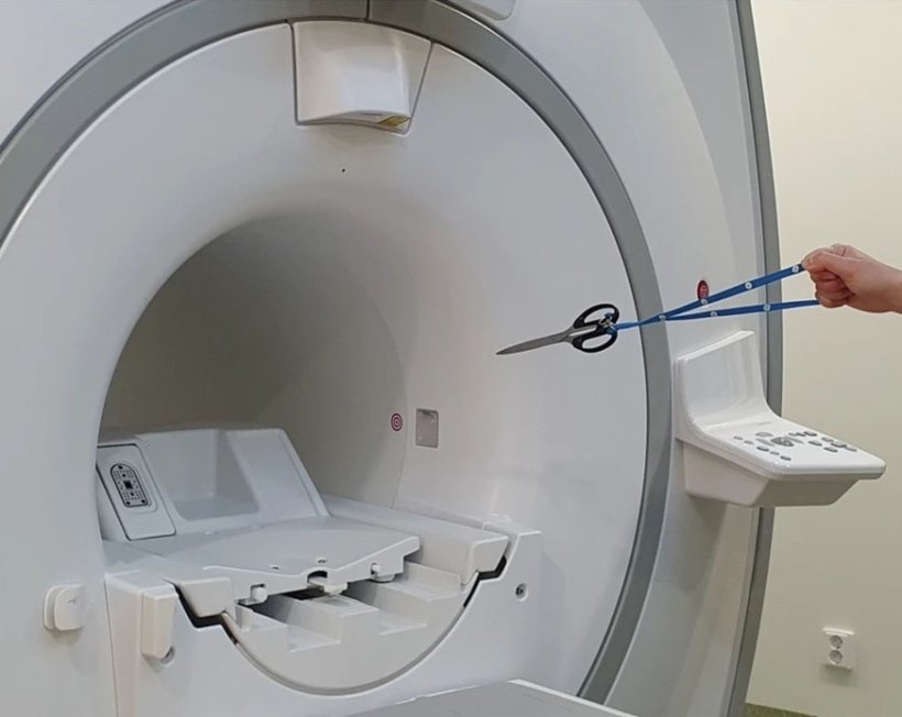 A pair of scissors is being pulled towards the maget of an MRI scanner. From...