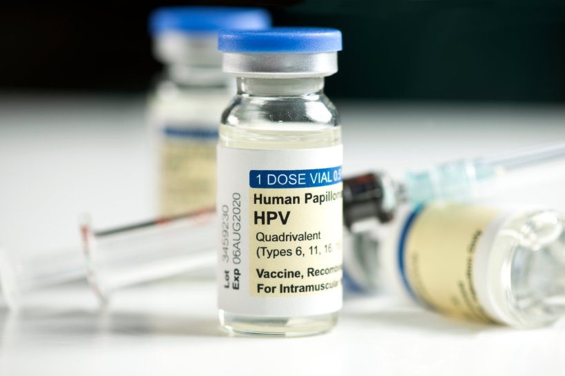Two vials of HPV (human papillomavirus) vaccine and a syringe on a white...