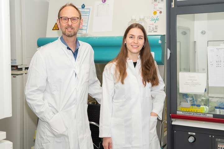 Zwei Personen in Laborkitteln stehen in einem Labor