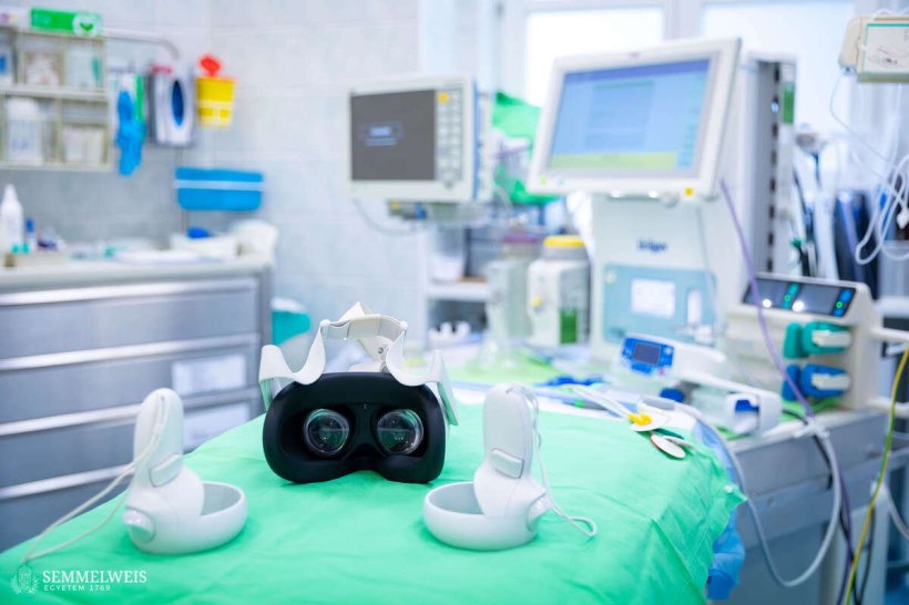 A VR headset and hand controller are lying on table covered in green surgical...