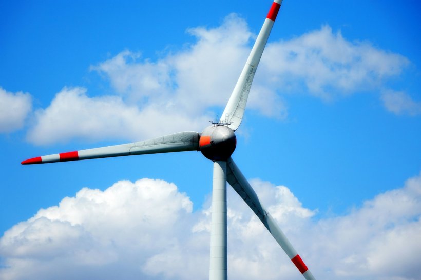 A white wind turbine with red markings on the turbine blades, against a...