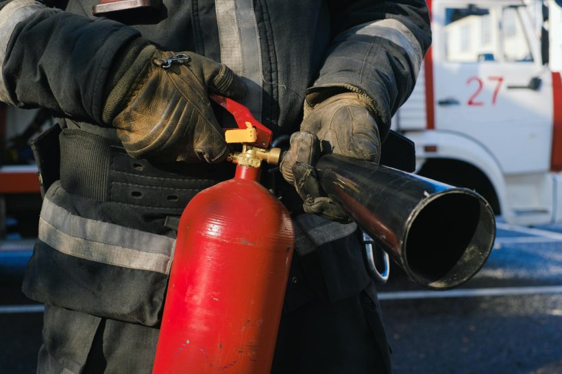Cropped photo of a fireman holding a fire extinguisher