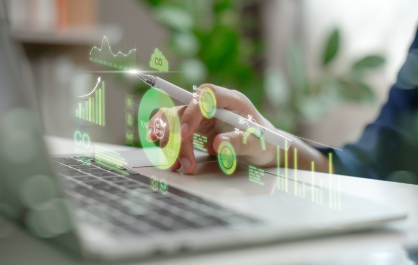 Cropped photo of a person operating a laptop computer, with icons related to...