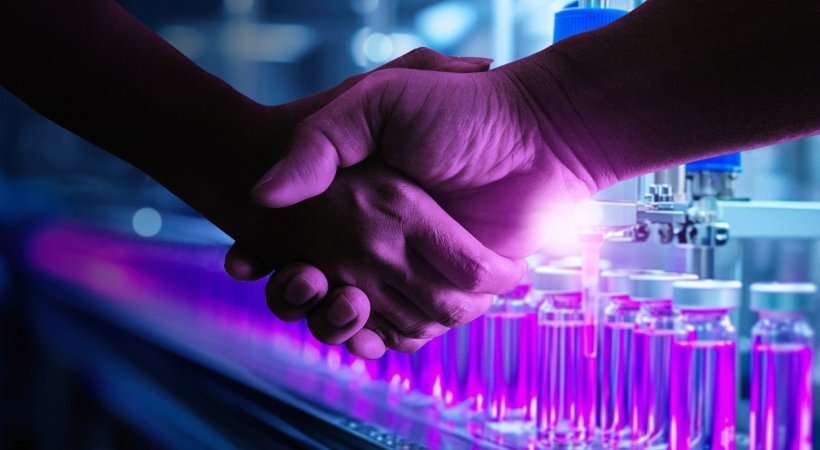 Closeup of two hands engaged in a handshake. In the background, laboratory...