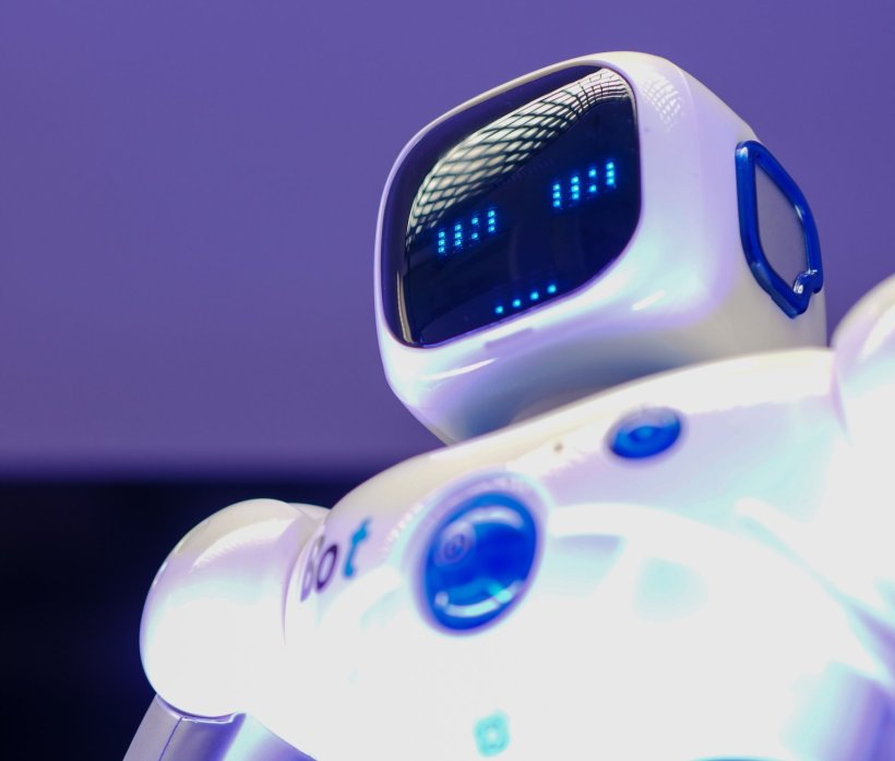 A futuristic white robot with a threatening look on its face display