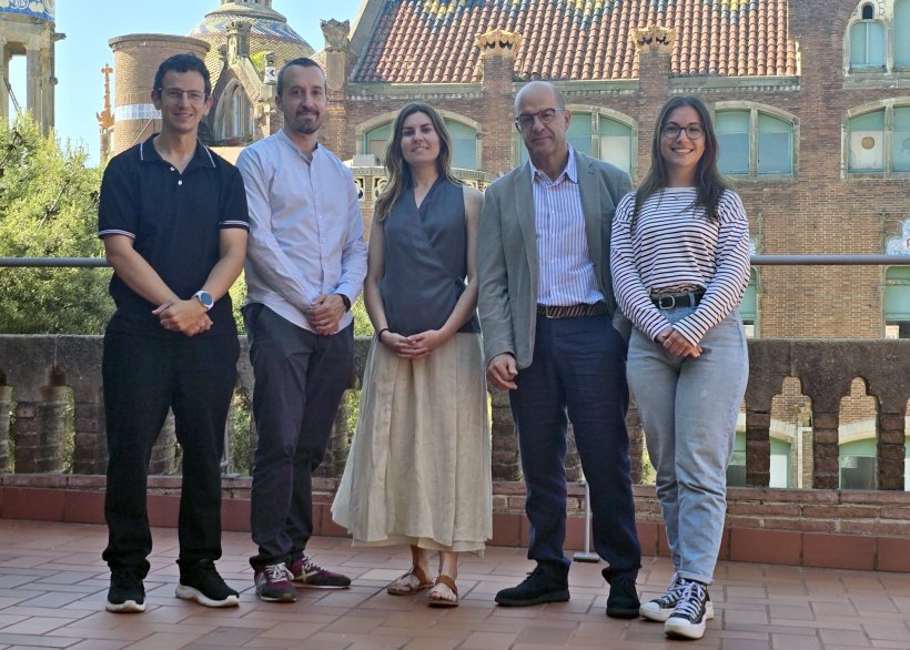 Five persons standing next to each other on a stone balcony for a group photo....
