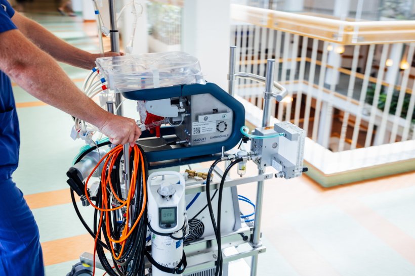 Ein Mediziner schiebt ein mobiles ECMO-Gerät über den Flur eines Krankenhauses