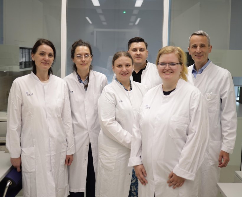 Sechs Personen in weißen Laborkitteln stehen für ein Gruppenfoto...
