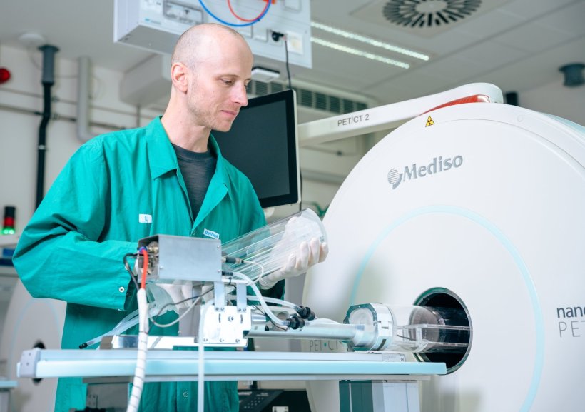 Dr. Martin Ullrich steht neben einem kleinen PET-Scanner für Tierversuche