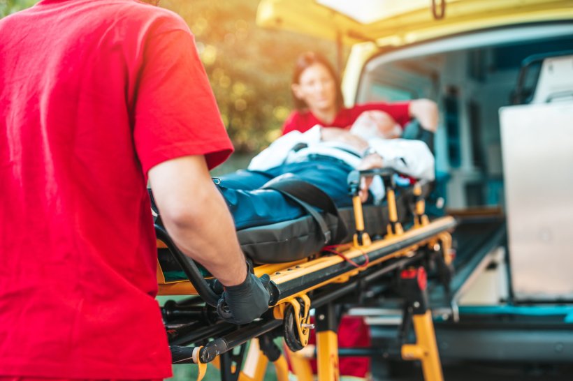 Zwei Rettungskräfte schieben einen Patienten auf einer Trage in einen...
