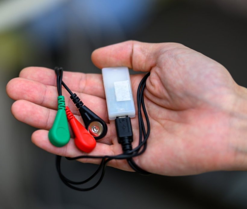 Closeup photo of a hand holding a wearable EEG monitoring device