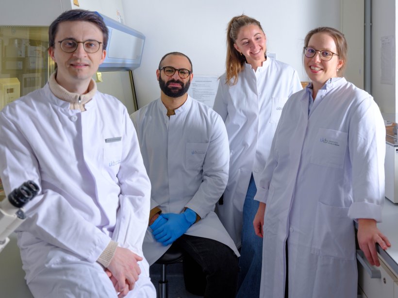 Vier Personen posieren für ein Teamfoto in einem medizinischen Labor