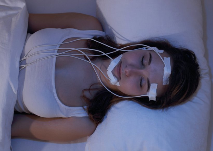 A young woman is sleeping in a medical sleep laboratory. Several electrodes are...
